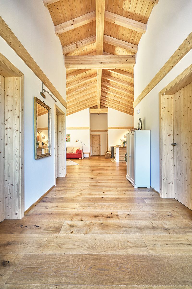 Holzhaus Innenraum mit Sichtbalkendecke und Holzböden
