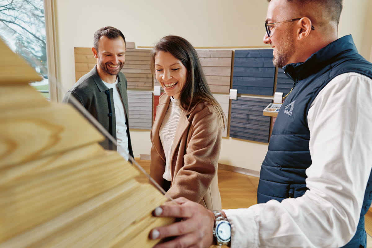 Junges Paar begutachtet Wandsystem für die weitere Planung ihres neuen Holzhauses