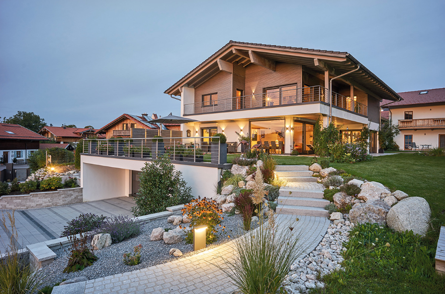 /files/dateien/H%C3%A4user/Foto%20Holzhaus/modernes-hanghaus-im-landhausstil-gruenwald-begruente-tiefgarage-garten.png
