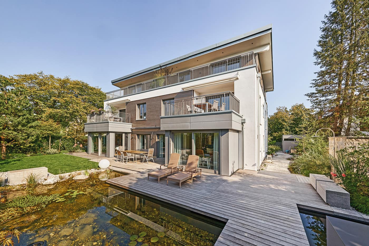 Mehrfamilienhaus aus Holz von Sonnleitner mit Naturteich umgeben von Bäumen