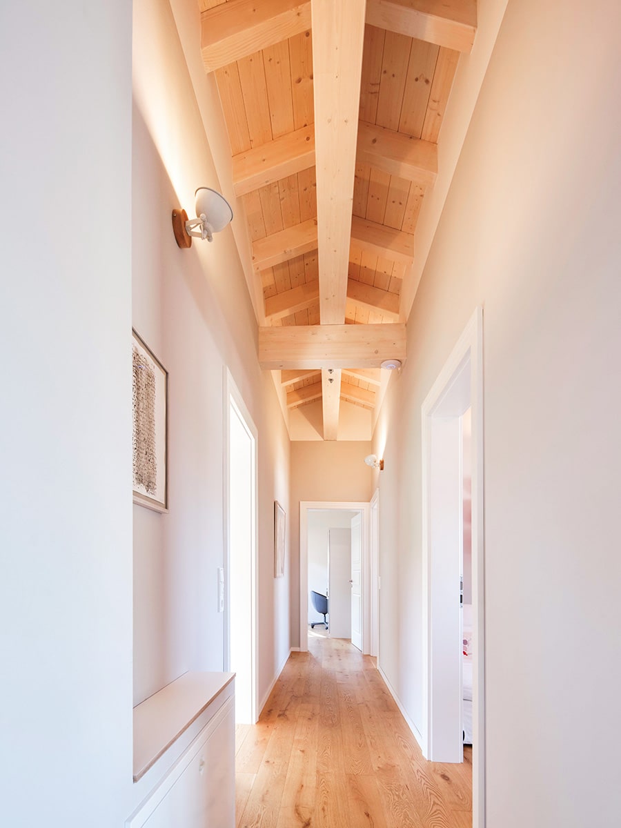 Heller Flur mit sichtbarer Holzbalkendecke bis zum First offen