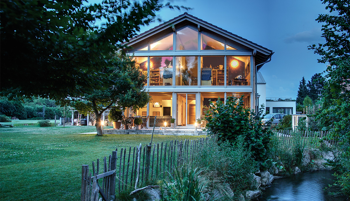 /files/dateien/H%C3%A4user/Kundenh%C3%A4user/Augsburg/modernes-holzhaus-augsburg-fensterfront-3fach-verglasung-parkaehnliche-gartenanlage-daemmerung.jpg