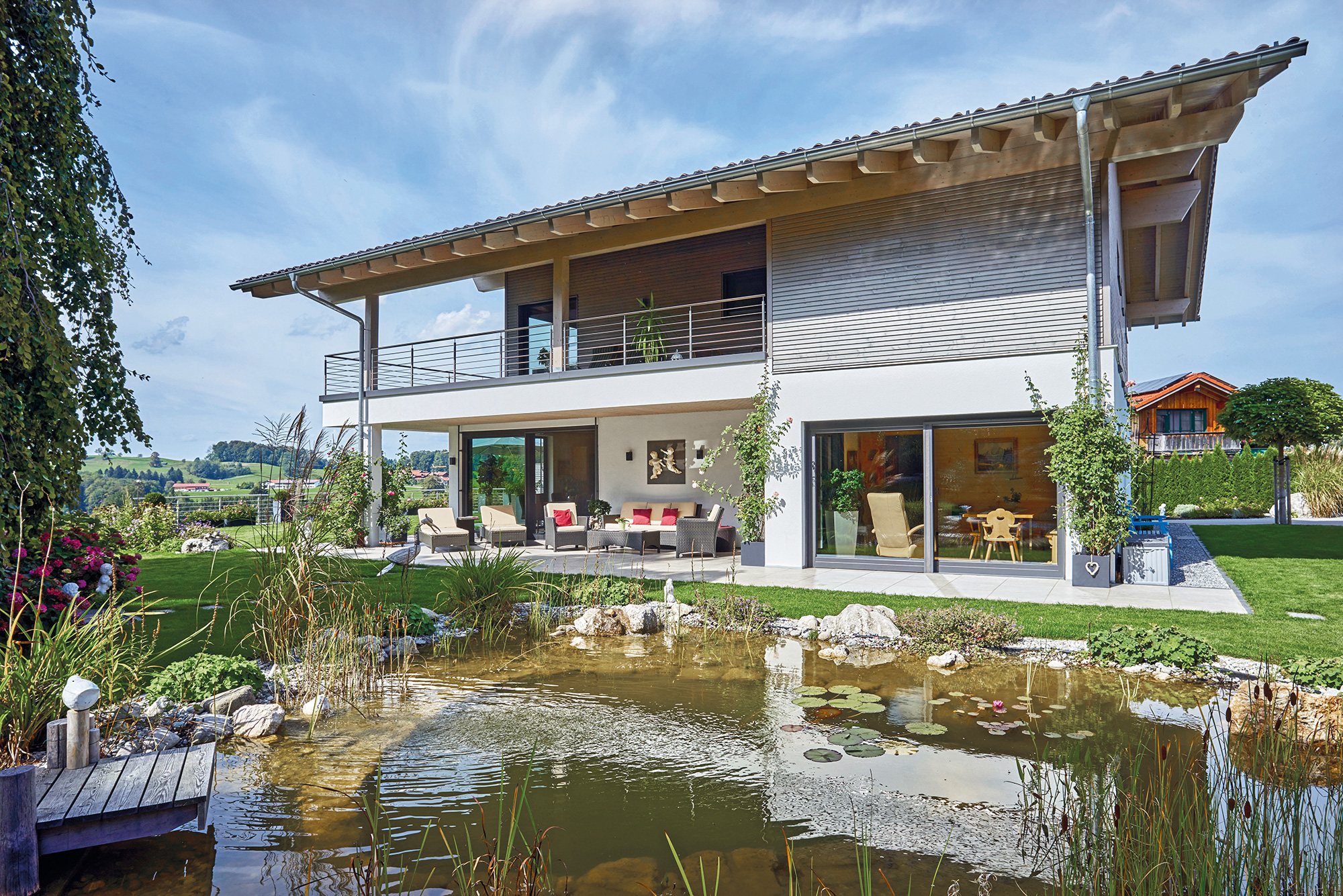 /files/dateien/H%C3%A4user/Kundenh%C3%A4user/Gr%C3%BCnwald/modernes-landhaus-gruenwald-gartenteich-terrasse-umlaufender-balkon.jpg