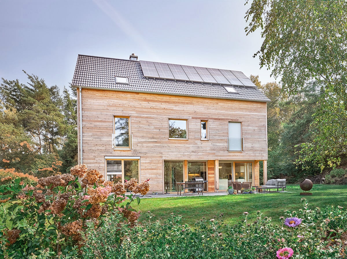 modernes Holzhaus mit natürliches Lärchenfassade, geringem Dachüberstand und asymmetrischen Fenstern in der Natur