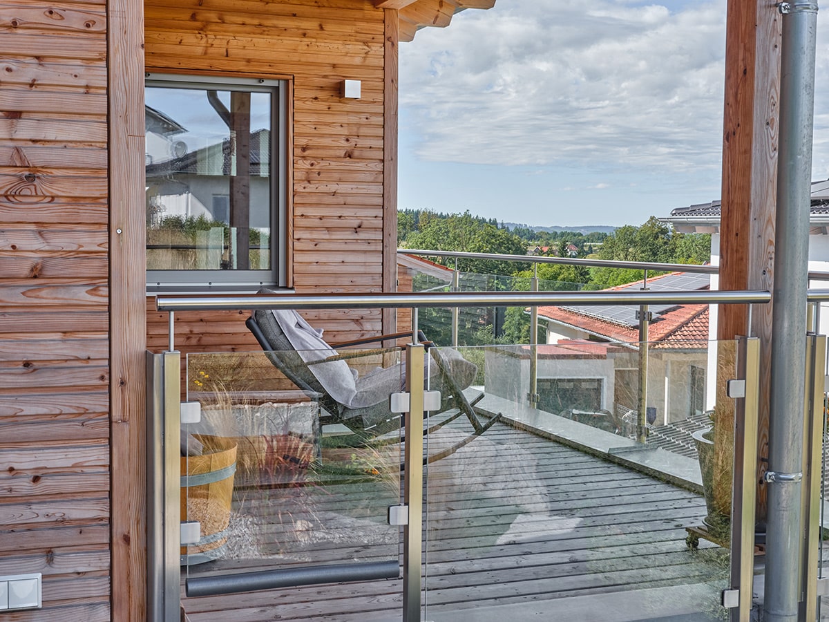 /files/dateien/H%C3%A4user/Kundenh%C3%A4user/Pfarrkirchen/Holzhaus-Bungalow-am-Hang_Massivholz-Fassade-Larche-Balkon-Aussicht-min.jpg