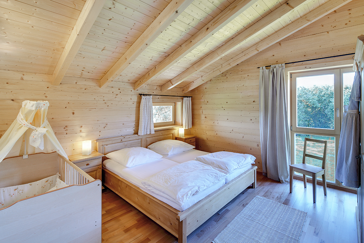 /files/dateien/H%C3%A4user/Kundenh%C3%A4user/Schiefer/Galerie/doppelhaus-holzhaus-schiefer-wohnraum-holzbalkendecke-holzboden-landhaus-schlafzimmer.jpg